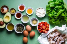 an assortment of food including eggs, tomatoes, lettuce and other ingredients on a green surface