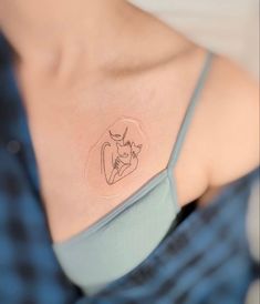 a woman's chest with a small tattoo on her left shoulder and an outline of a cat