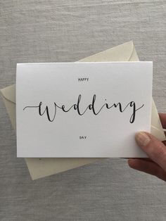 someone holding up a card with the word happy wedding written in cursive writing