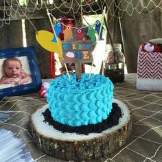 a blue cake sitting on top of a wooden table next to a framed photo and other items