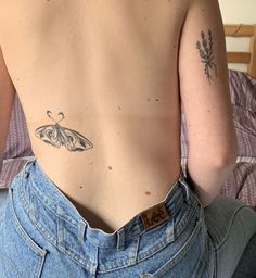 a woman with a butterfly tattoo on her back, sitting in bed and looking at the camera