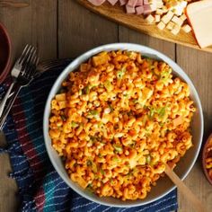 a bowl filled with macaroni and cheese next to other foods on a table