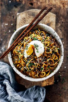 an overhead view of a bowl of noodles with eggs and chopsticks on the side