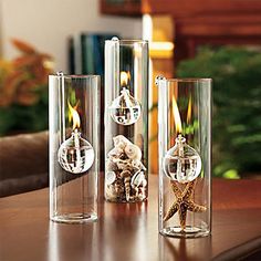 three clear glass vases with candles in them sitting on a table next to a candle holder