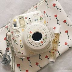 a white camera sitting on top of a table next to a small bottle of perfume