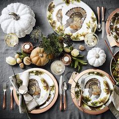 a table set for thanksgiving dinner with turkey plates, silverware and gold rimmed dishes