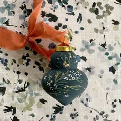 an ornament with a ribbon on it sitting on a floral print tablecloth