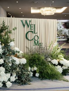 white flowers and greenery in front of a welcome sign