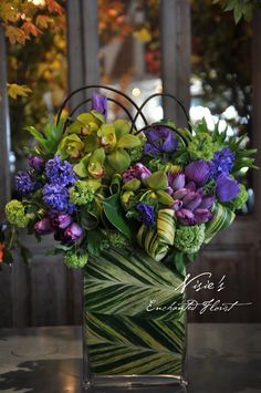 a vase filled with lots of purple and green flowers