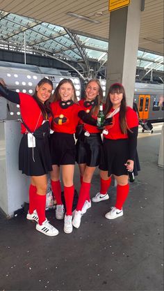 four girls dressed in red and black posing for the camera with their arms around each other