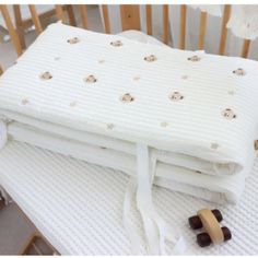 a baby crib mattress with teddy bears on it and two wooden rocking chairs in the background