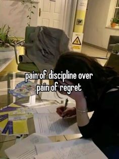 a woman sitting at a table with papers and pen in her hand, writing on the paper