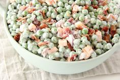 a bowl filled with peas and bacon on top of a table