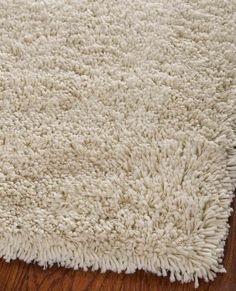 a white rug on top of a wooden floor next to a wood flooring board