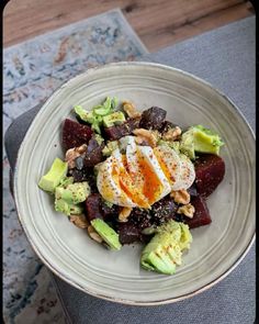 a white bowl filled with food on top of a wooden table next to a rug