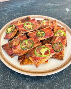 bacon and jalapeno slices on a white plate with black granite counter top