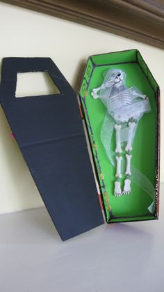 a box with a skeleton in it sitting on top of a table next to a paper bag