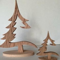 two wooden christmas trees sitting on top of a white table next to eachother