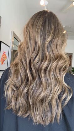 the back of a woman's head with long wavy blonde hair in a salon