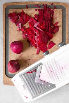 chopped red onions on a cutting board next to a grater and knife with the peels removed