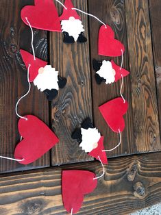 some red and white hearts hanging from string on wooden planked wall with strings attached to them