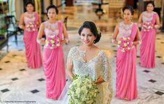 a woman standing in front of a group of other women wearing pink dresses and holding bouquets