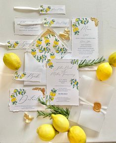 wedding stationery with lemons and greenery laid out on a white tablecloth