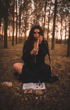 a woman sitting on the ground with her hands in her mouth and holding an umbrella