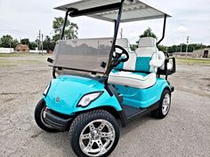 a blue and white golf cart parked on the side of the road in an empty lot