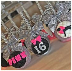 cupcakes decorated with pink and black frosting are displayed on a wooden table