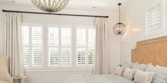 a bed sitting in a bedroom next to a window with shutters on both sides