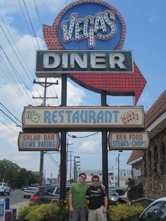 two men standing in front of a restaurant sign