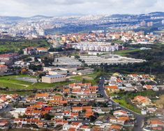 an aerial view of a city with lots of buildings and green hills in the background