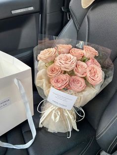 a bouquet of pink roses sitting in the back seat of a car next to a white bag