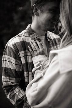 a man holding a baby in his arms while standing next to a woman's chest