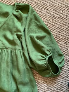 a green dress laying on top of a carpet next to a pair of black shoes