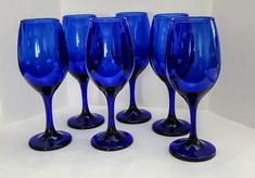 six blue wine glasses are lined up in a row