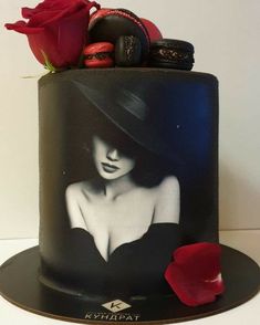 a black cake with a red rose on top and an image of a woman wearing a hat