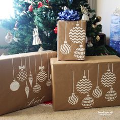 three brown boxes with ornaments on them sitting in front of a christmas tree