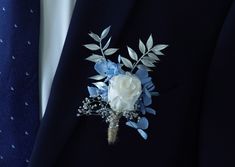 a boutonniere with blue and white flowers on the lapel of a suit