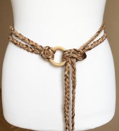 a white mannequin wearing a brown belt with gold rings and braided rope