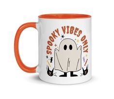 a white and orange coffee mug with an image of a ghost saying spooky vibes only