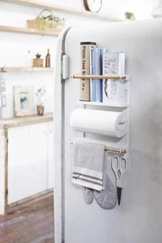 a white refrigerator with some books and scissors on the shelf next to it is a towel rack