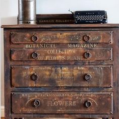 an old chest of drawers with writing on it and a typewriter sitting on top