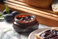 a jar of jam sitting on top of a table next to blueberries and bread