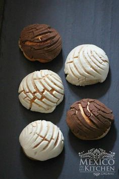 four cookies with chocolate and white frosting on a black surface