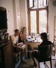 three people sitting at a table in a kitchen