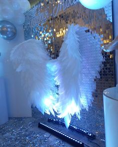 white feathers on display in front of a mirror with disco balls and lights behind it