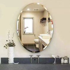 a bathroom with a sink, mirror and vase on the counter in front of it