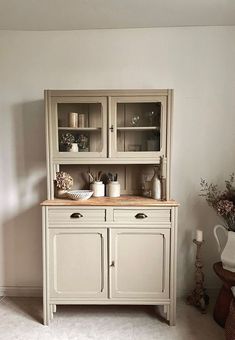 a white china cabinet with glass doors and drawers